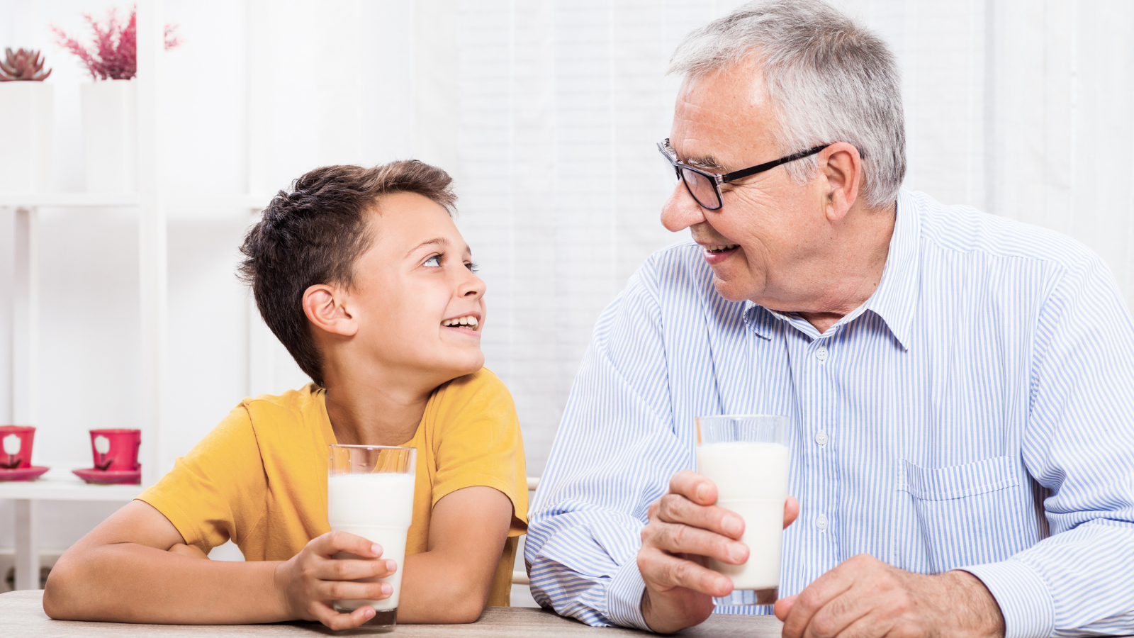 Smiling grandfather and grandson drinking milk together. A joyful family moment promoting healthy habits for all generations.